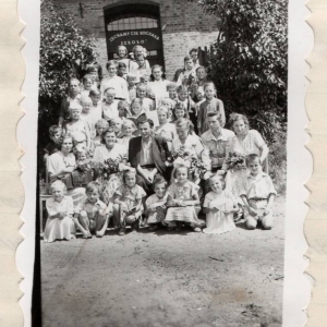 Zakończenie roku szkolnego 1952/1953 w  Szkole Podstawowej w Maszewie Lęborskim. Na zdjęciu: Komitet Rodzicielski, grono pedagogiczne oraz uczniowie przed szkołą.  Zdjęcie pochodzi z kroniki  szkolnej.